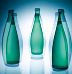 Tre dubbel exponerade gröna Perrier flaska mot vit bakgrund